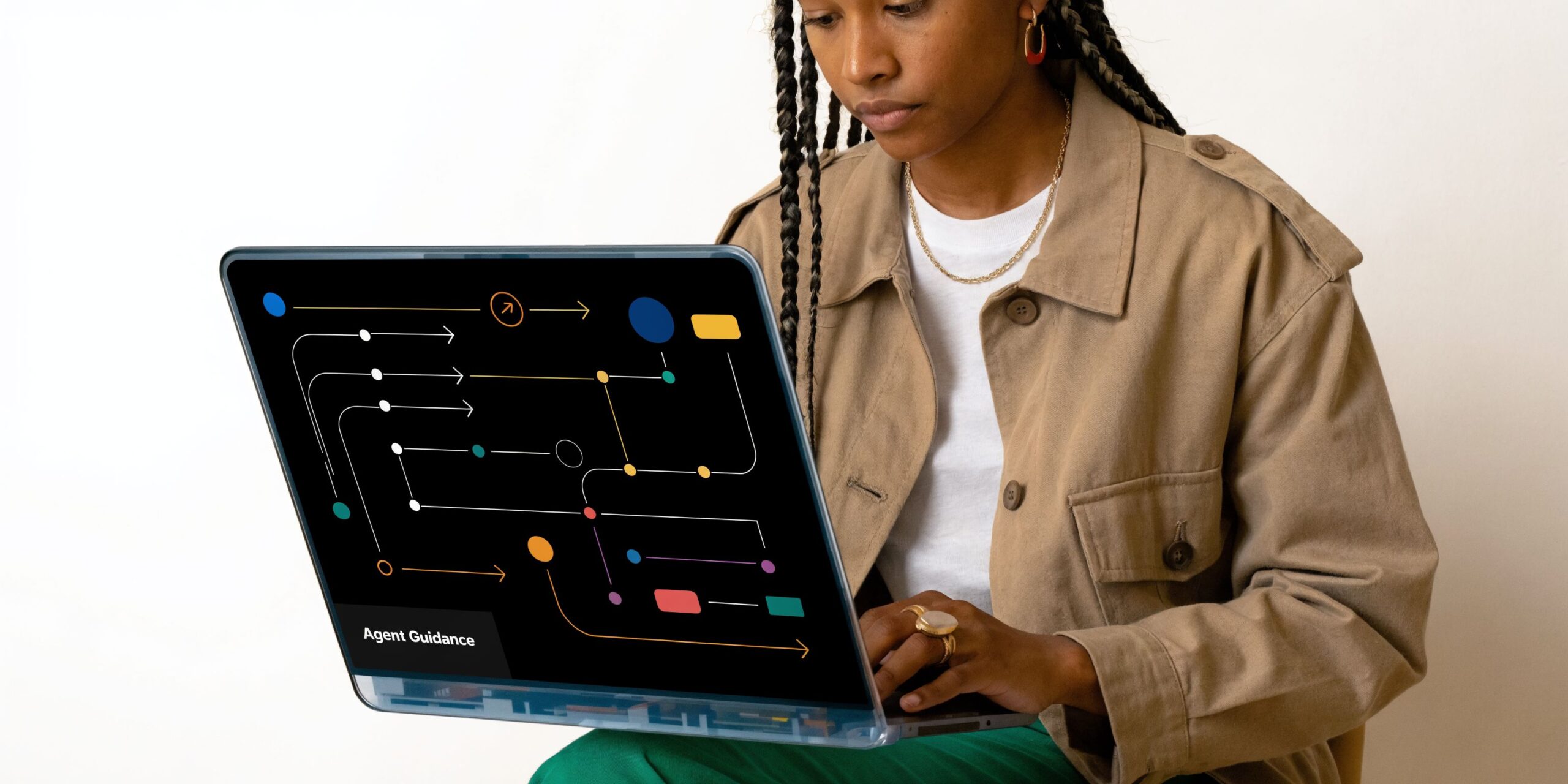 A young professional woman using a laptop displaying an abstract diagram representing AI agent guidance workflows.